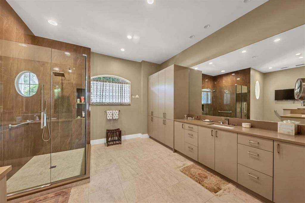 Newly remodeled Owners spa like bath with abundant storage, seperate vanities, large glass walk in shower, quartz counters and custom fixtures