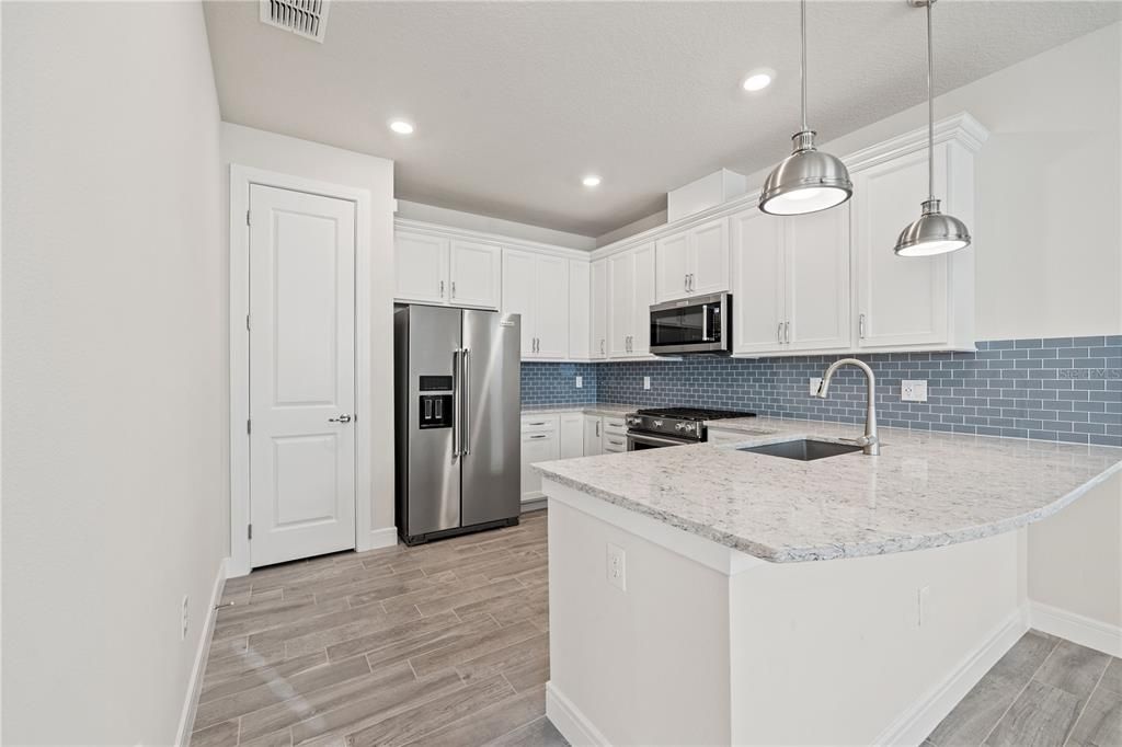 The designer kitchen showcases 3cm quartz countertops, 2”x4” glass backsplash, a pantry, pendant light package, stainless steel appliances including Kitchen Aid side by side water in the door refrigerator, dishwasher, exterior vented microwave and a gas range.