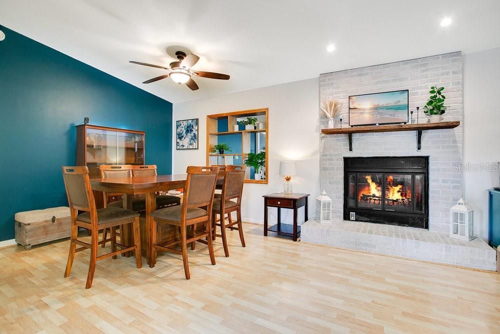 White washed, brick, wood burning fireplace and peacock blue accent wall with mid-century modern shelving