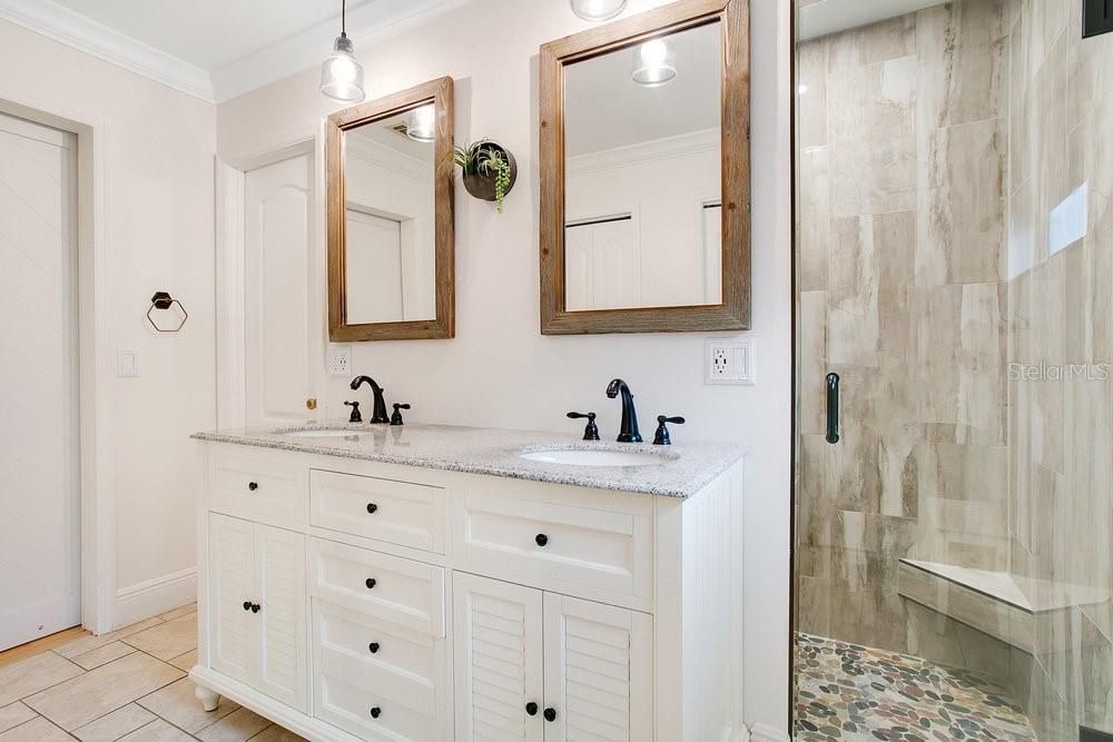 Primary Bathroom Updated in 2019. River Rock shower flooring and accent wall, moden tile with bench seating. Dual sink vanity, mirrors and lights. Dual closets.
