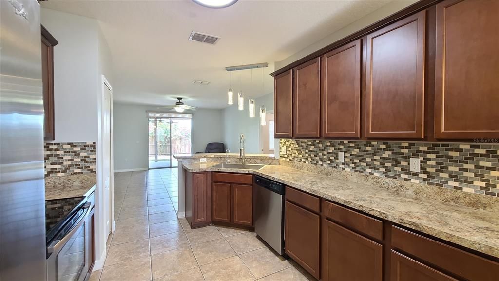 The large kitchen features a breakfast bar and over looks the living room with a great view of the lovely backyard.