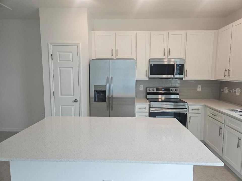 Kitchen - Quartz Counters and bar with eat in space, stainless smart appliances and lake views.