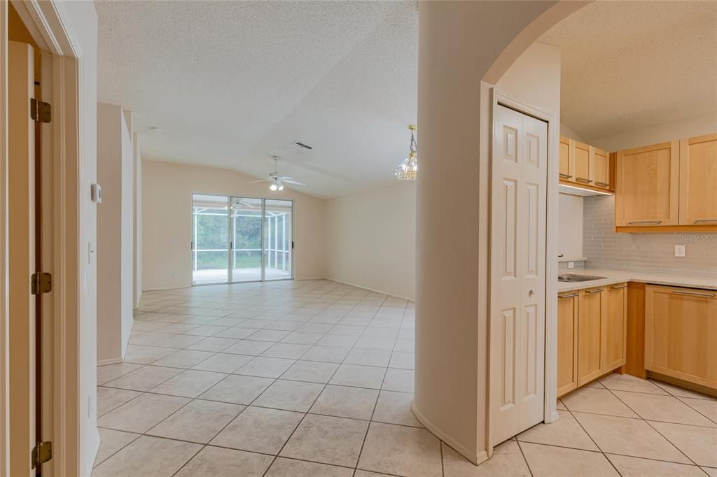 Looking into the kitchen from the breakfast bar with undermounted lights illuminating the quartz countertops and glass tiles.