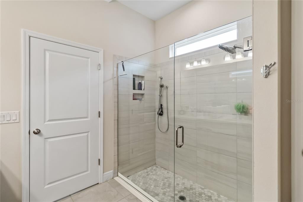 Large shower with seamless glass doors in primary bathroom.