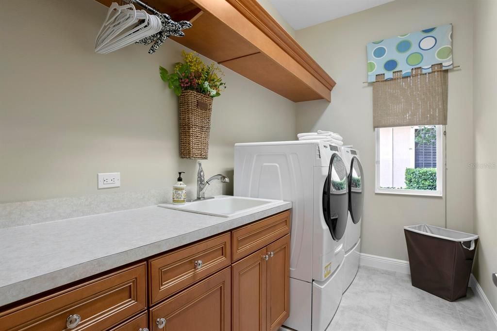 Laundry with hardwood cabinets. hanging rod, sink and folding area.