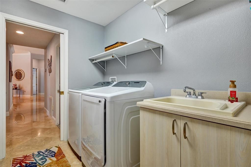 Laundry room has sink, a area for hanging clothes, cabinets for storage.