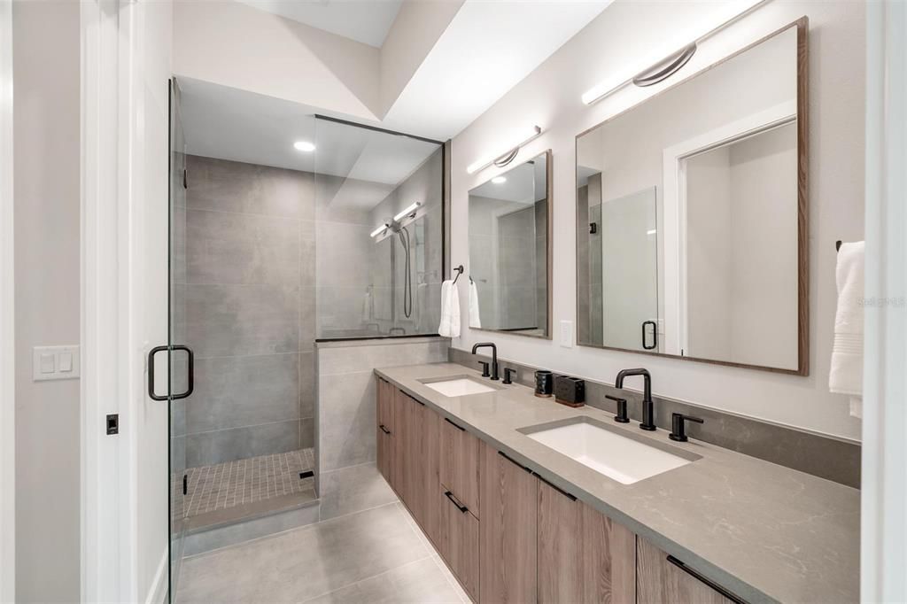 The primary bathroom boasts dual vanity sinks, a spacious walk-in shower, water closet, and quartz countertops.