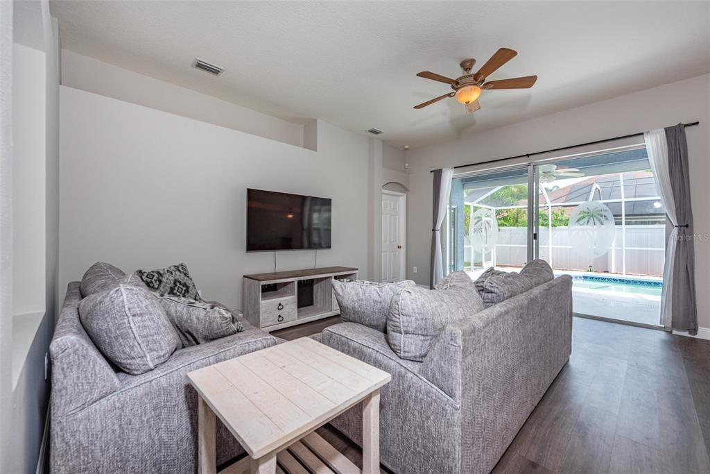 The spacious kitchen seamlessly connects to the large family room, boasting high ceilings, lots of natural light and a sliding glass door leading to a large back porch & screened lanai.