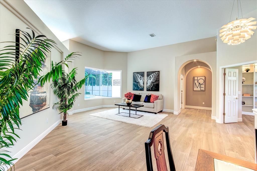 Open concept living room and dining room which looks out over the oool.