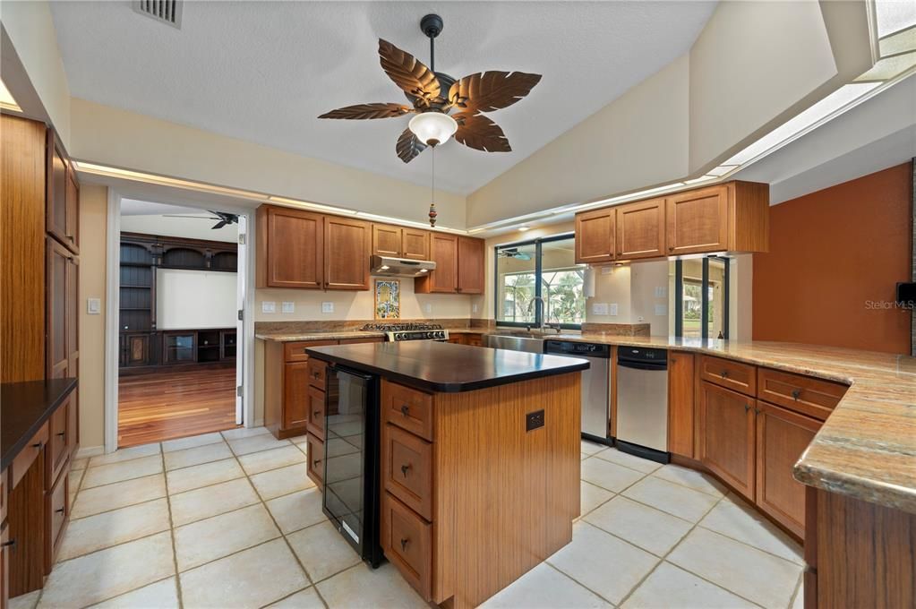 Spacious Kitchen with high ceilings, gas range, d/w, trash compactor, wine cooler, stainless refrigerator and view of pool and canal from window over the farmhouse stainless sink with R/O water