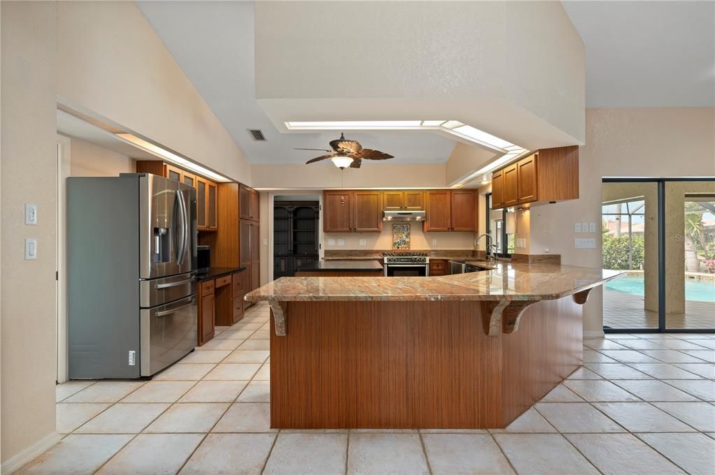 View of kitchen from dining area adjacent to kitchen. Breakfast bar wraps the corner with its granite countertop.