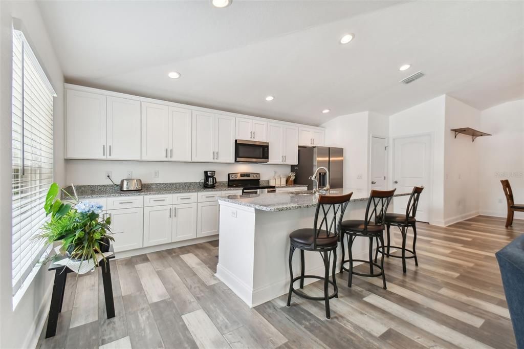 Large Kitchen with white cabinets, stone counters and stainless steel appliances