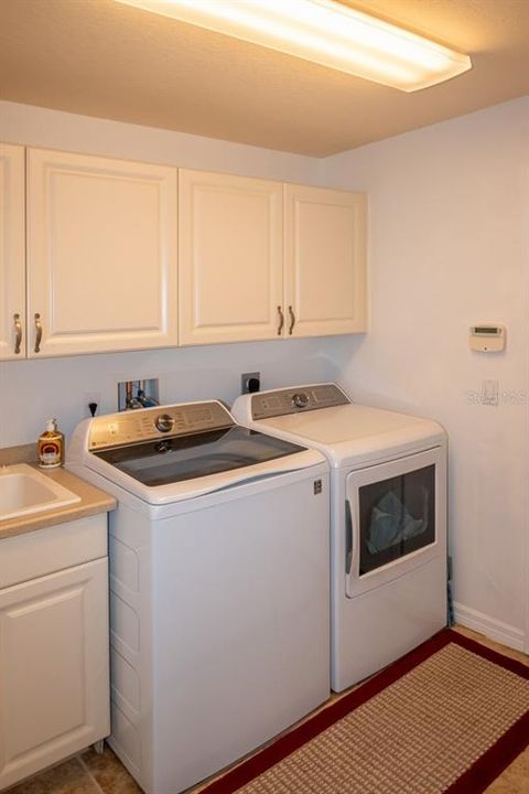 Laundry room with cabinets for extra storage and utility sink.