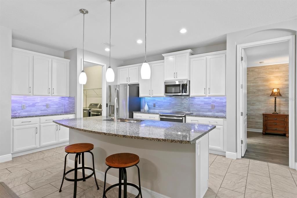 The kitchen features a large breakfast bar and pendant lighting