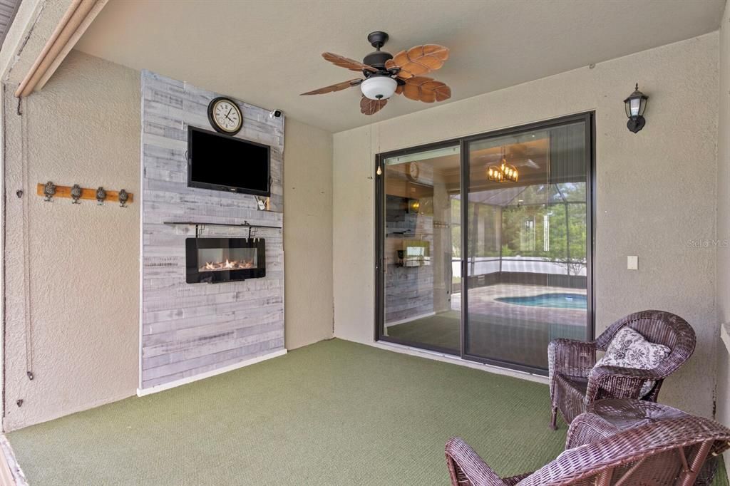 The covered lanai includes a TV, electric fireplace and wood accent wall