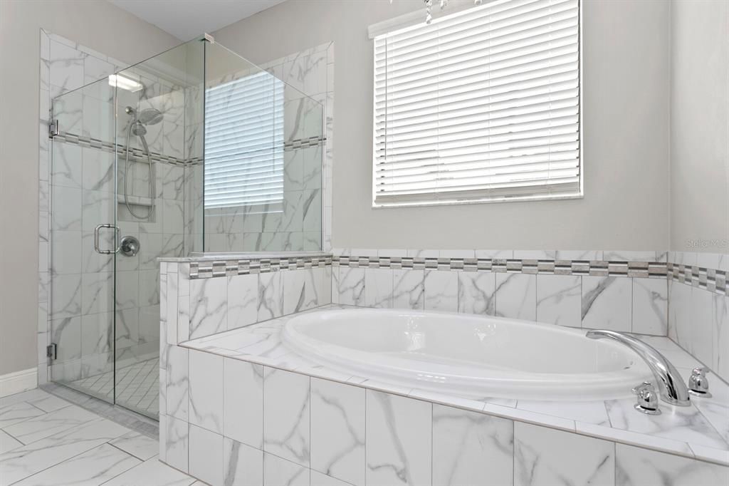 The master bath has a large soaking tub with chandelier and frameless glass shower