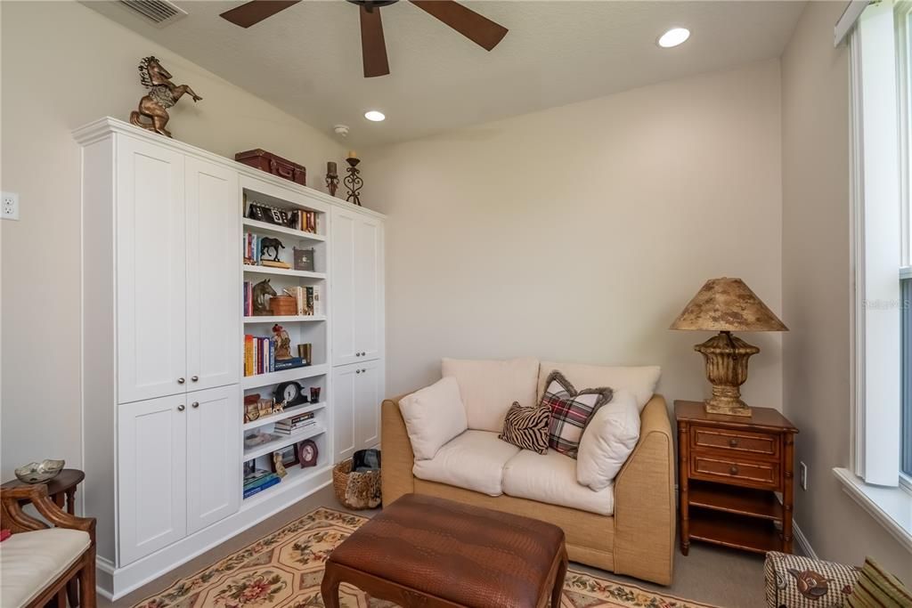 Den with custom shelves and cabinets off of the living room