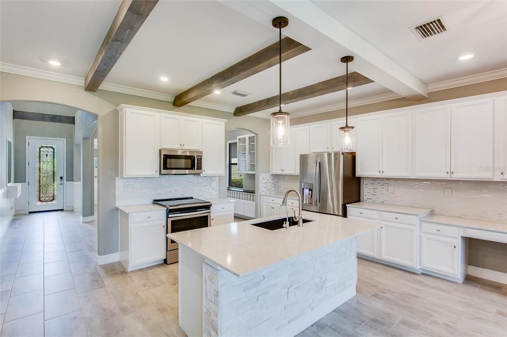 With tones of gray and white, ceiling molding and trim, and upgraded lighting this kitchen is very inviting.