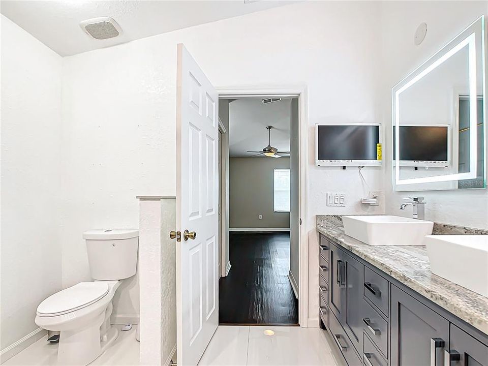 The En-suite primary bathroom has been beautifully remodeled with a soaking tub, separate shower, updated dual-vessel sinks, granite countertops, and illuminated defogging mirrors.