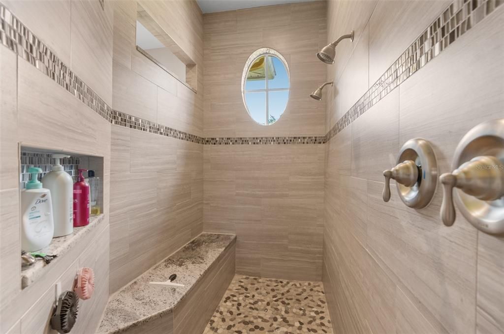 Master shower with built-in seat and multiple showers.