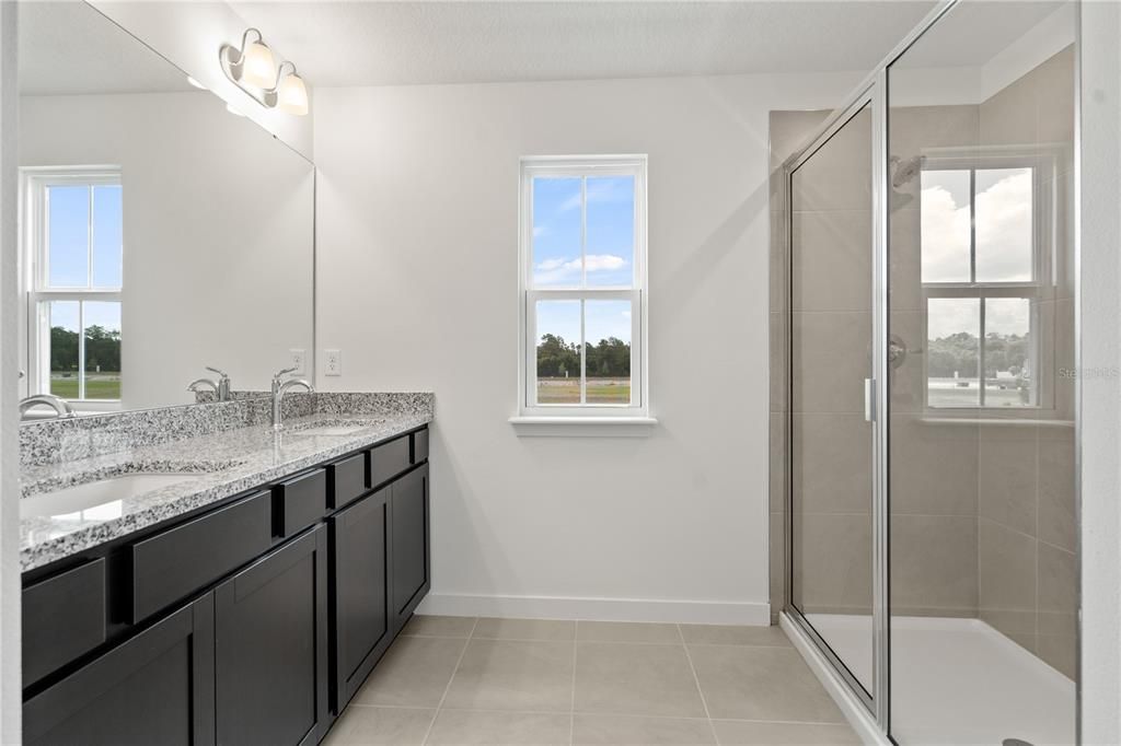 Spacious primary bathroom with two sinks and lots of light.