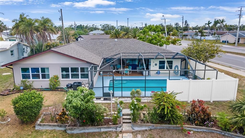 Rear home, new screened enclosure, new privacy fence around north side of pool and yard