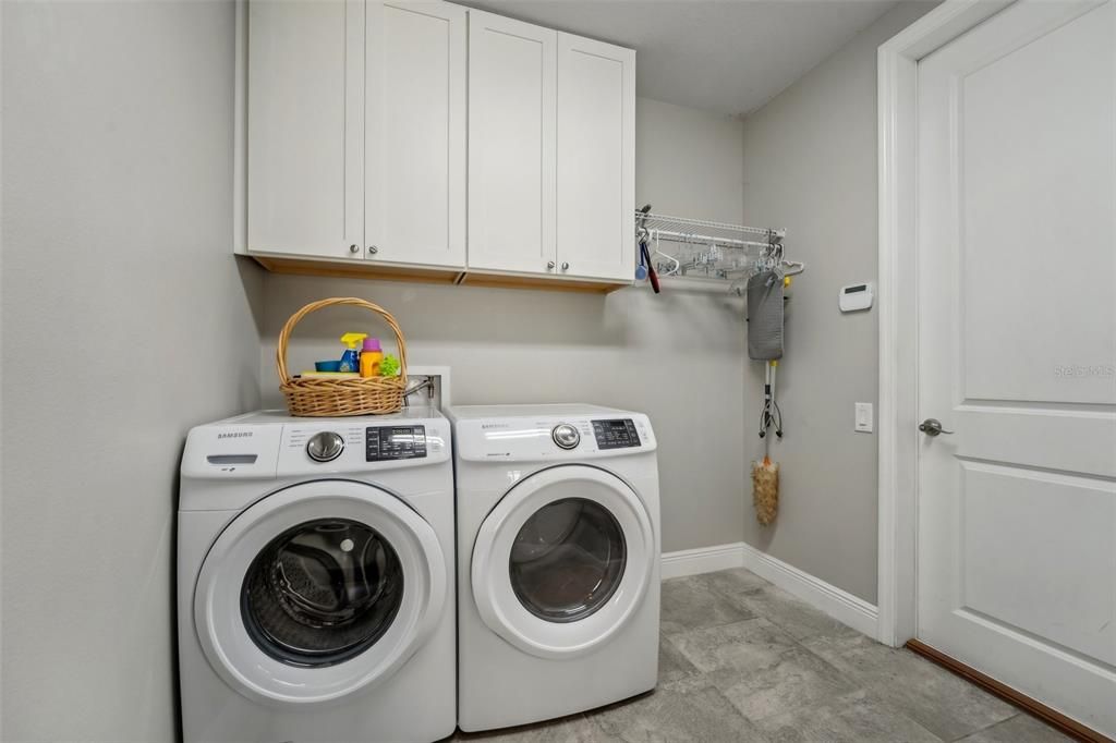 Laundry room with storage cabinets and closet on opposite wall