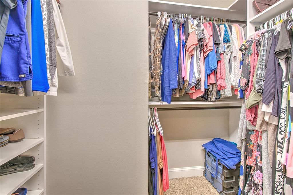 Primary walk in closet with custom built ins