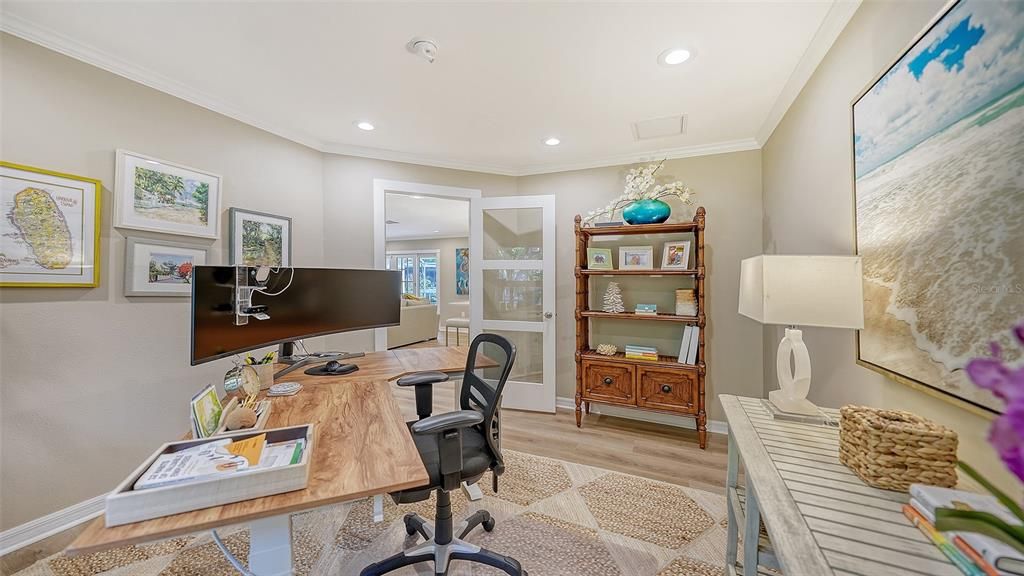 Spacious home office with crown molding and glass door.