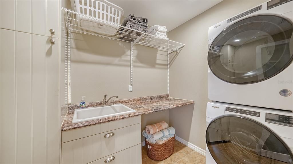 Spacious laundry room with storage, utility sink, tile floor and Whirlpool washer & dryer. There is also a large walk in pantry.