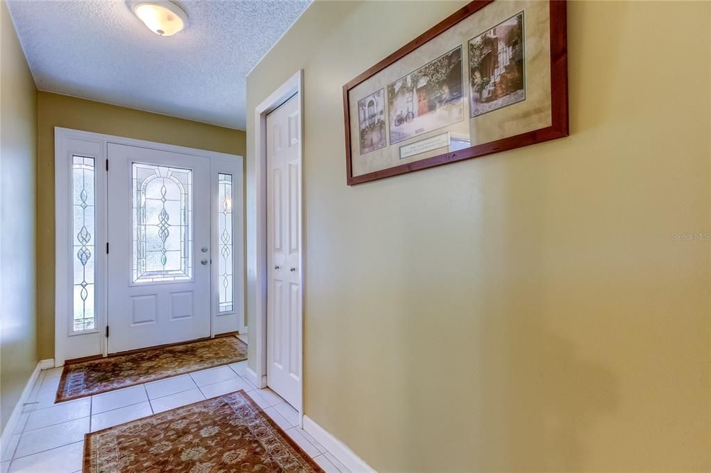 Foyer with decorative glass door, coat closet and laundry room entry into garage.