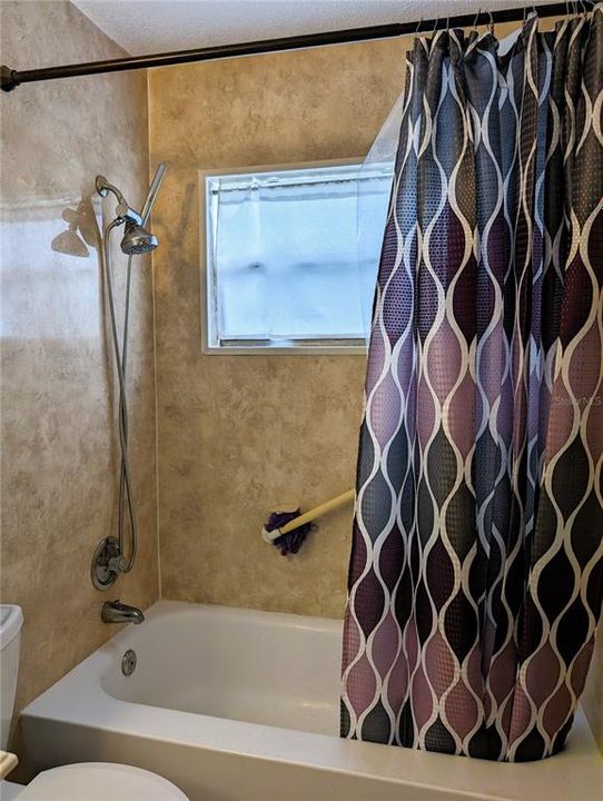 Bathtub offers grab bar, updated plumbing fixtures, surround and large window.