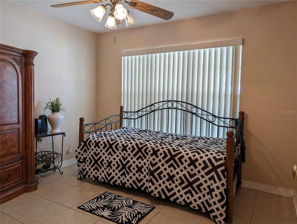 Guest bedroom had tile floor, ceiling fan w/light, neutral decor and bright natural light from large window.