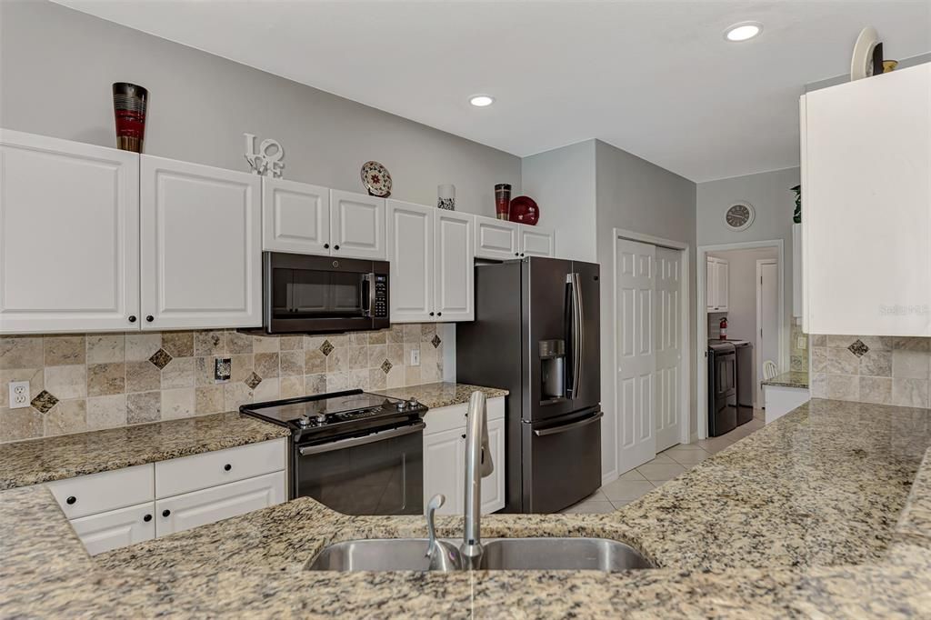 beautifully upgraded granite counters, tumbled tile back splash newer suite of slate appliances including sleek slide in range