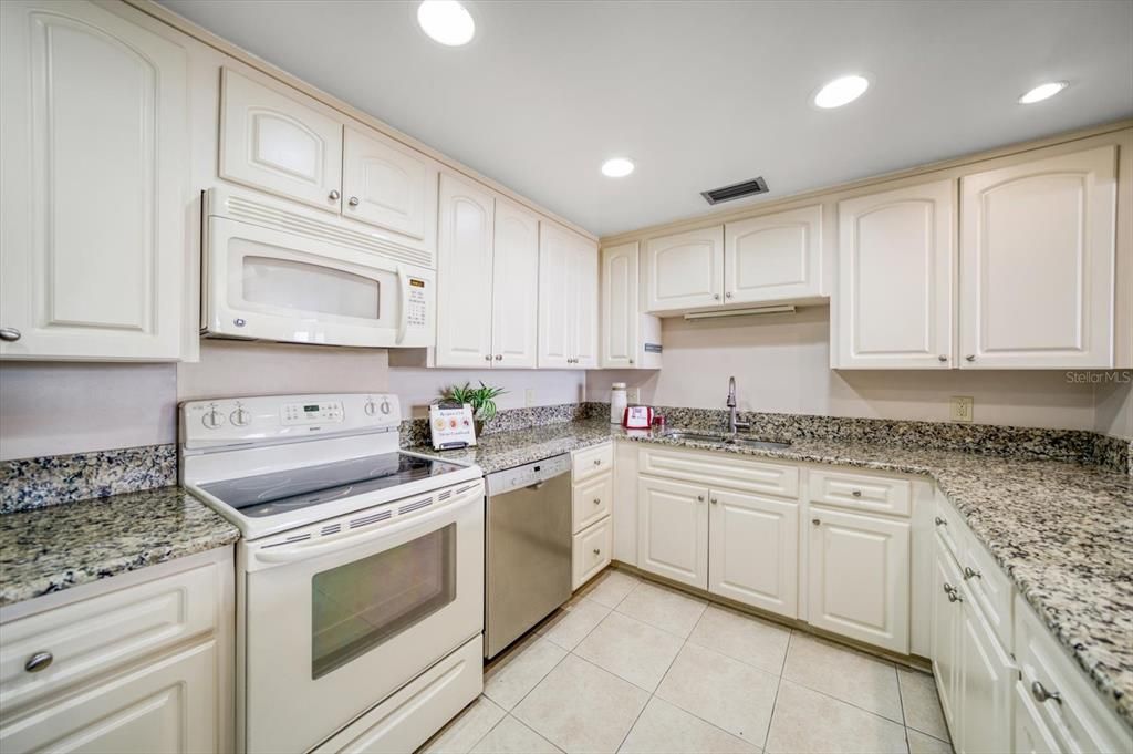 Fully equipped kitchen of neutral colors, granite counters and notable storage area