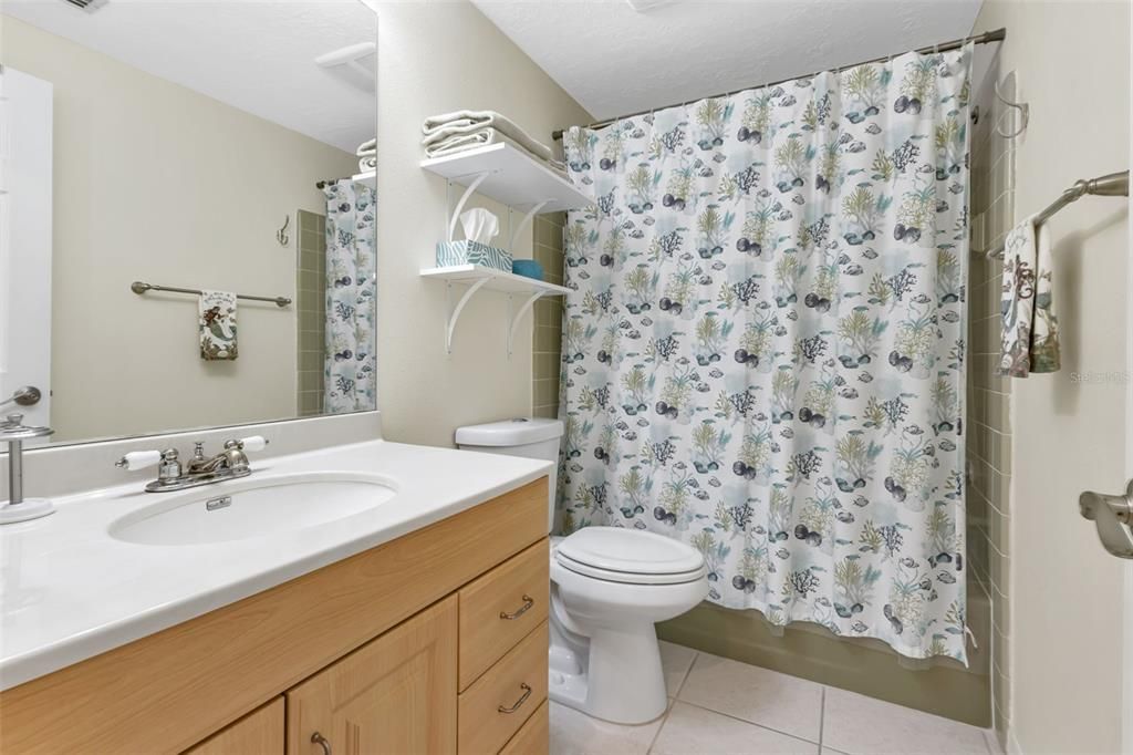 Guest bathroom features single sink and shower/tub combo.