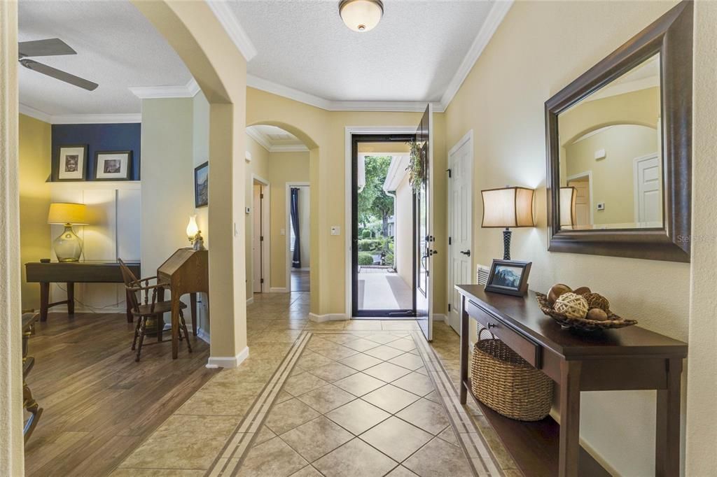 Foyer entryway w/ tile border inlay, glass storm door, leaded glass front door & crown molding