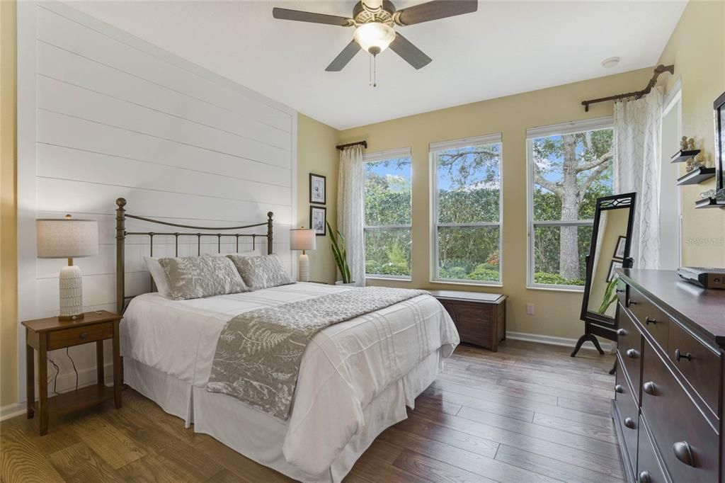 15' x 12'6" Primary Bedroom w/ decorative wood accent wall, luxury vinyl floor & a ceiling fan