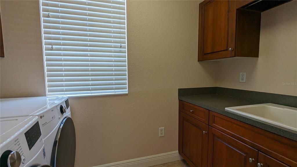 True utility room with extra storage cabinets, utility sink and hang bar