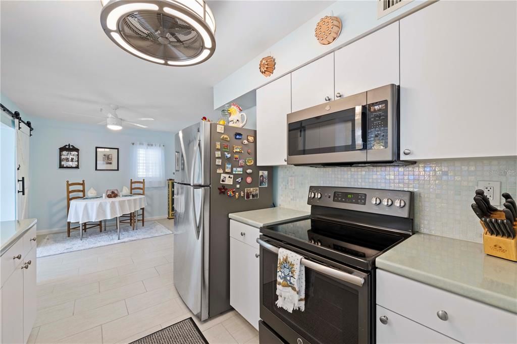 Galley style kitchen with solid surface counters, ample cabinetry, and stainless steel appliances.