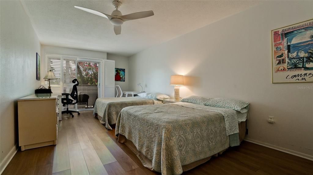 SECOND OR GUEST BEDROOM WITH TWO SEPARATE BEDS, NEW OVERHEAD FAN & VINYL PLANK FLOORING.DESK & DESK CHAIR ARE EXCLUDED FROM SALE. BERMUDA SHUTTERED SLIDERS LEAD TO COURTYARD.