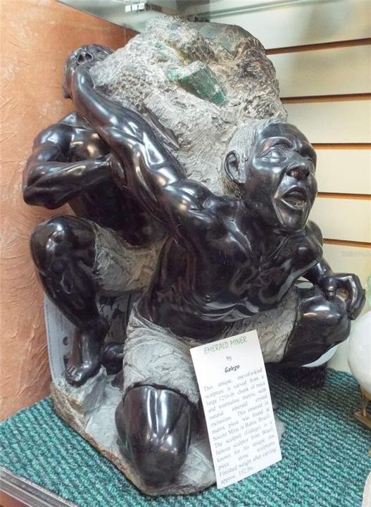 Galego:  This unique, one-of-a-kind sculpture is carved from a large 1,250 lb chunk of mica and tourmaline matrix, with natural Emerald crystal inclusions.  This Emerald in matrix piece was found at Socoto Mine in Bahia, Brazil.  The sculptor, Galego, is a famous sculptor from Brazil known for his unique one-piece stone sculptures.  Finished weight after carving approximately 152 lbs.