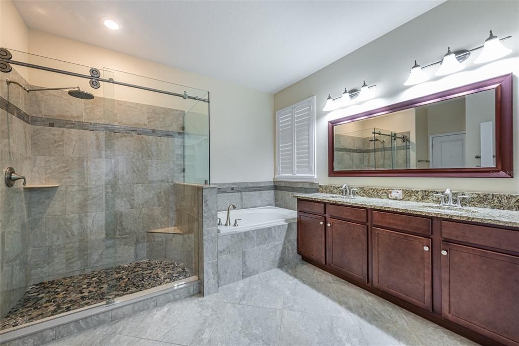 Have you ever seen a sliding barn style door on a frameless glass shower before?  There's a rain shower head, custom stone tile and a built-in bench. Dual sinks with granite counters and lots of cabinets for storage and a garden tub for soaking. There is also a water closet with a door for privacy.