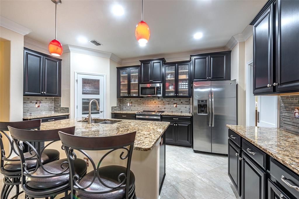 Notice all the granite counter space there is to work.  You'll love the stainless steel appliances, rain glass cabinet doors, glass top stove and double door refrigerator.  The dry bar on the left would make a great coffee bar.