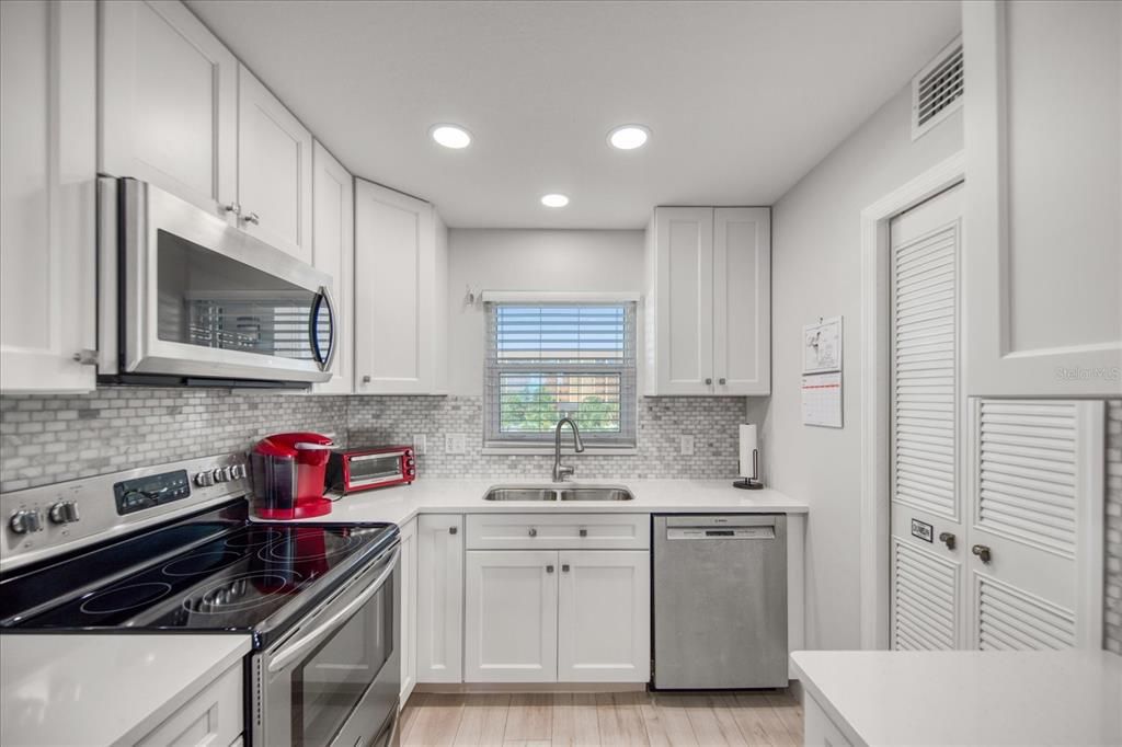 Fully remodeled kitchen with stainless steel appliances, white shaker cabinets, quartz counters, plus a pantry.