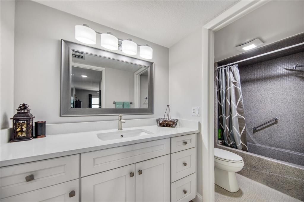 Updated bathroom with quartz counters and white shaker cabinets.