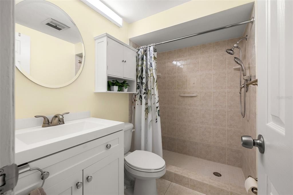 Renovated bathroom features an updated vanity, comfort height toilet and custom tiled walk-in shower for ease of accessibility.