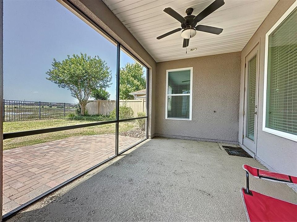 Screened lanai with additional pavered area, fenced yard and lake view