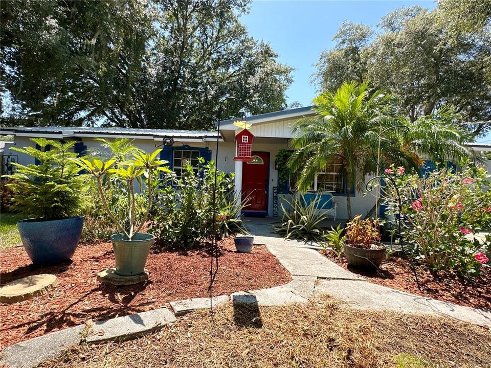 Lush fruit plants and flowers along pathways in front of the home