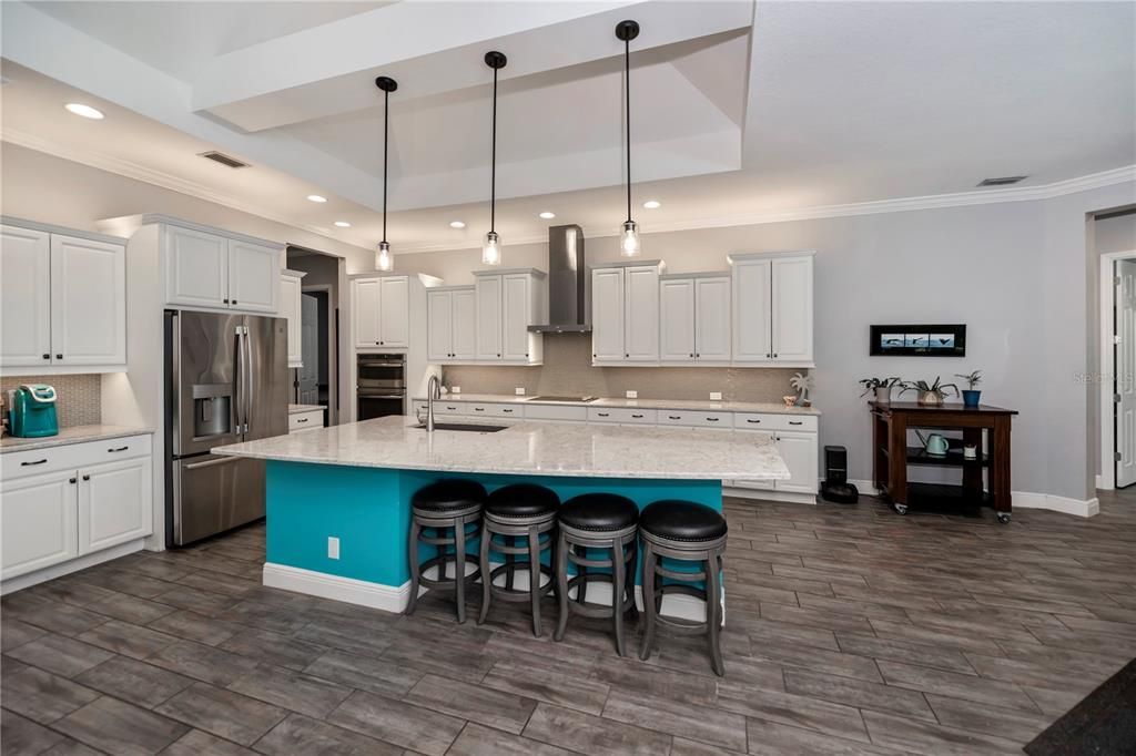 Designer chef kitchen featuring an extra large island complete with service sink and breakfast bar